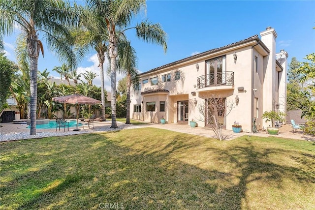 rear view of house featuring a yard, a balcony, and a patio area