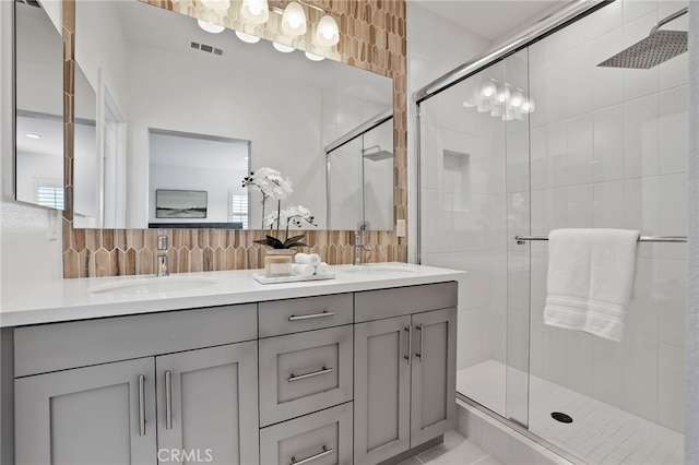 bathroom with backsplash, vanity, and a shower with door