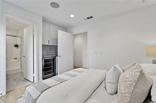 bedroom with light wood-type flooring and beverage cooler