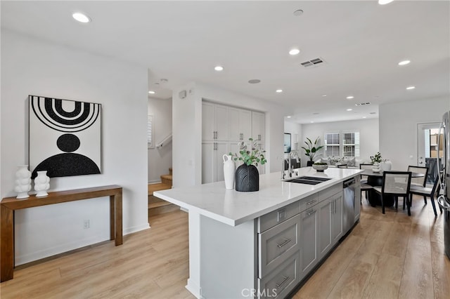 kitchen with a center island with sink, gray cabinetry, light hardwood / wood-style floors, sink, and dishwasher