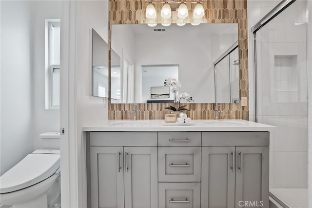 bathroom with plenty of natural light, vanity, a shower with door, and toilet