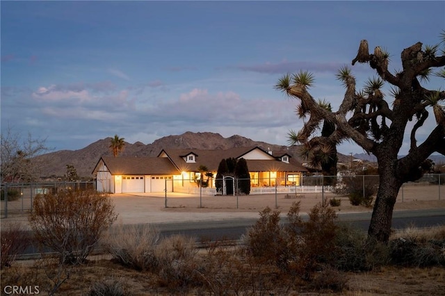 view of front of property with a fenced front yard, driveway, an attached garage, and a mountain view