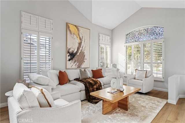 living room featuring light hardwood / wood-style flooring, plenty of natural light, and vaulted ceiling