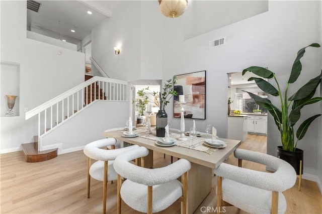 dining room with light hardwood / wood-style flooring and a high ceiling