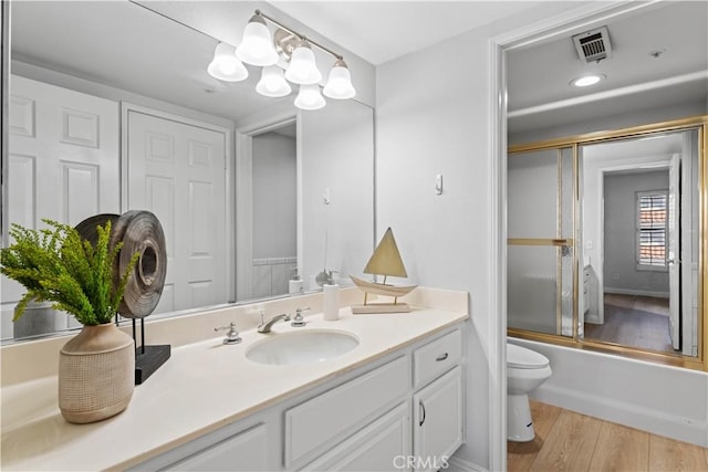 full bathroom featuring hardwood / wood-style flooring, an inviting chandelier, toilet, vanity, and shower / bath combination with glass door