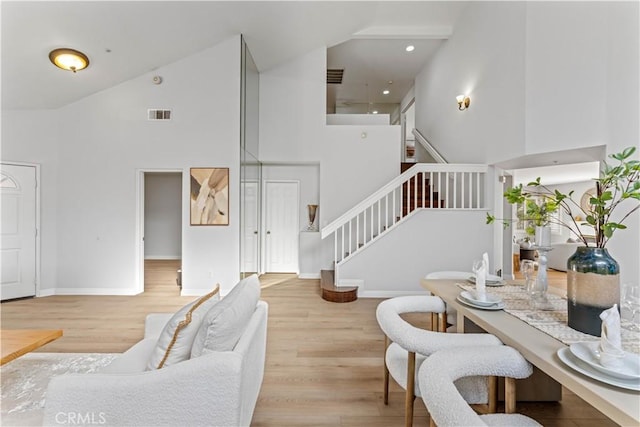 living room with light hardwood / wood-style flooring and high vaulted ceiling