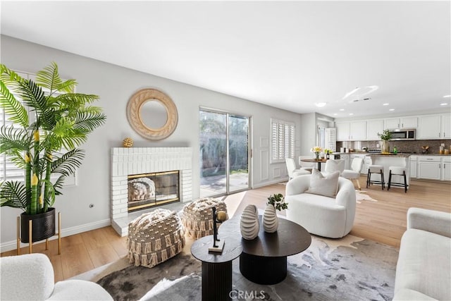 living room featuring light hardwood / wood-style flooring and a brick fireplace