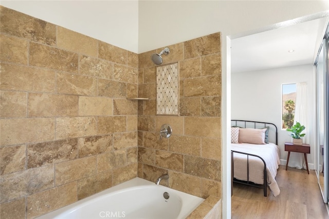 bathroom with hardwood / wood-style floors and tiled shower / bath