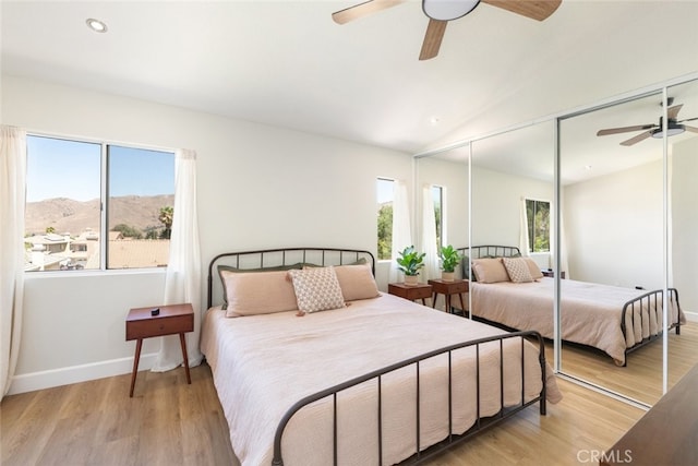 bedroom featuring a mountain view, multiple windows, and light hardwood / wood-style flooring