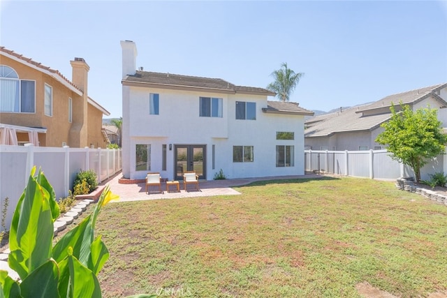 rear view of property featuring a patio area, a yard, and french doors