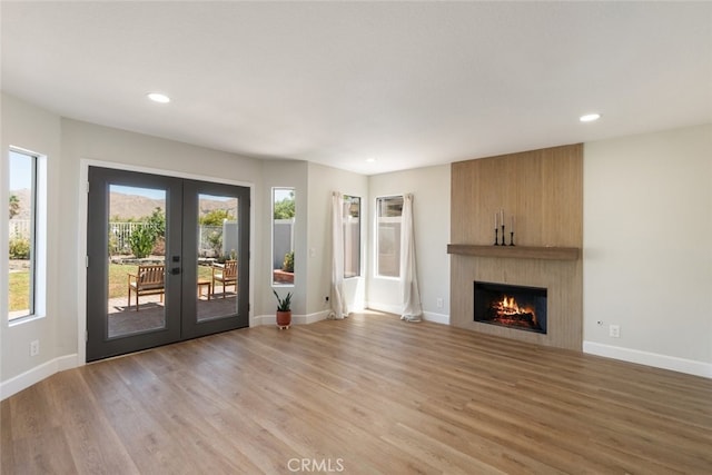 unfurnished living room featuring light wood-type flooring, french doors, and a fireplace