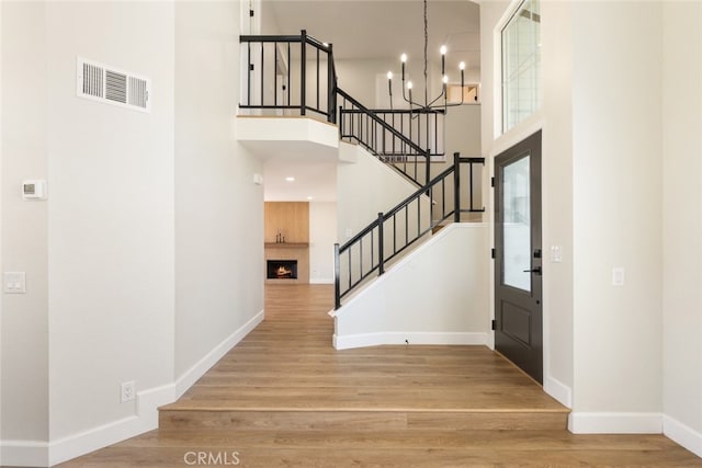 foyer featuring a chandelier, wood-type flooring, and a towering ceiling