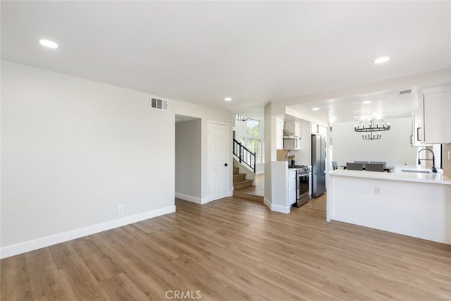 kitchen featuring white cabinetry, sink, stainless steel appliances, and light hardwood / wood-style floors