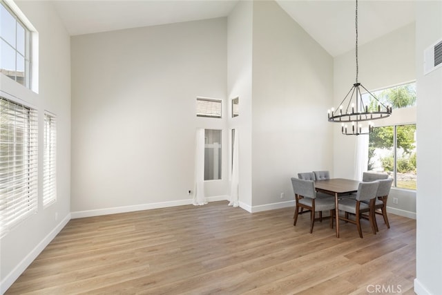 dining room featuring light wood-type flooring, high vaulted ceiling, and a chandelier