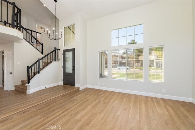 entrance foyer featuring a notable chandelier, light wood-type flooring, a wealth of natural light, and a high ceiling