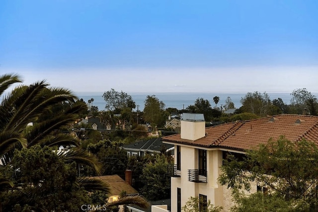 exterior space with a chimney, a water view, a tiled roof, and stucco siding