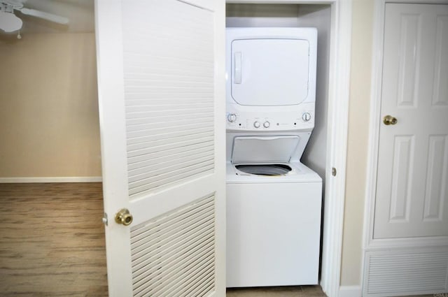 clothes washing area featuring stacked washing maching and dryer, ceiling fan, and hardwood / wood-style flooring