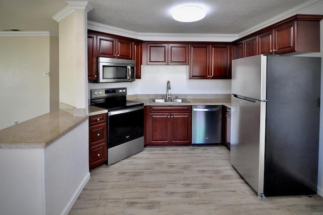 kitchen with kitchen peninsula, light hardwood / wood-style flooring, sink, ornamental molding, and appliances with stainless steel finishes