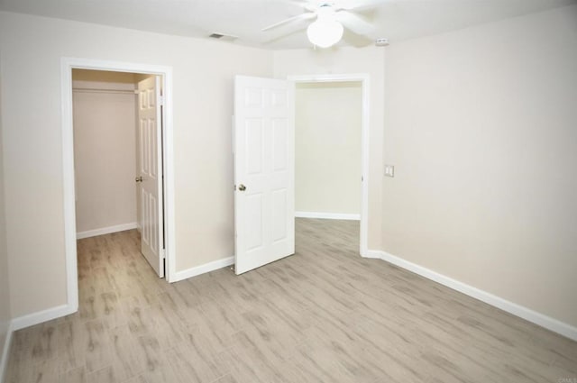 unfurnished bedroom with ceiling fan, light hardwood / wood-style flooring, a closet, and a spacious closet