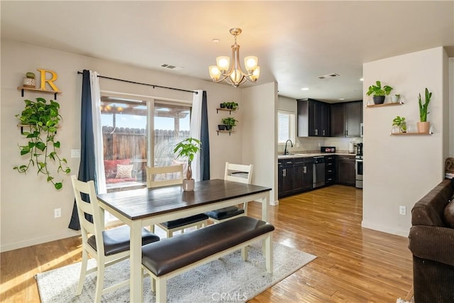 dining area featuring sink, a chandelier, and light wood-type flooring