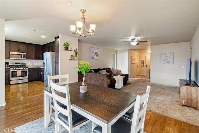 dining area featuring light wood-type flooring and ceiling fan with notable chandelier