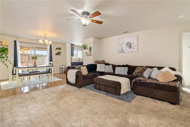 living room featuring ceiling fan with notable chandelier and light hardwood / wood-style flooring