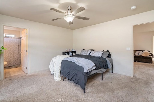 bedroom featuring light colored carpet, ceiling fan, and ensuite bath