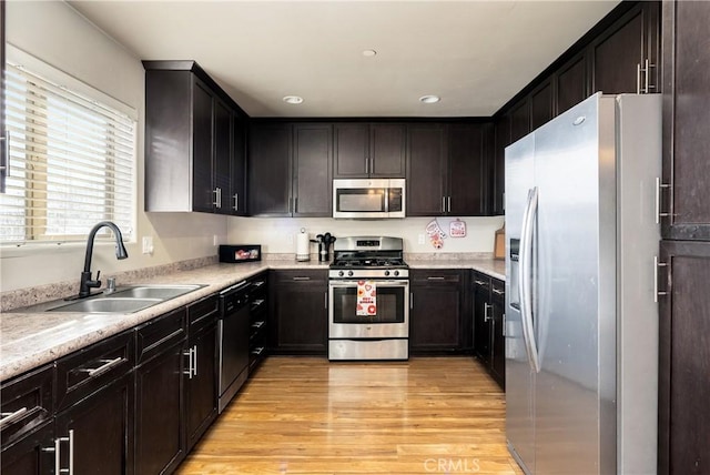 kitchen with sink, light stone countertops, stainless steel appliances, and light hardwood / wood-style floors