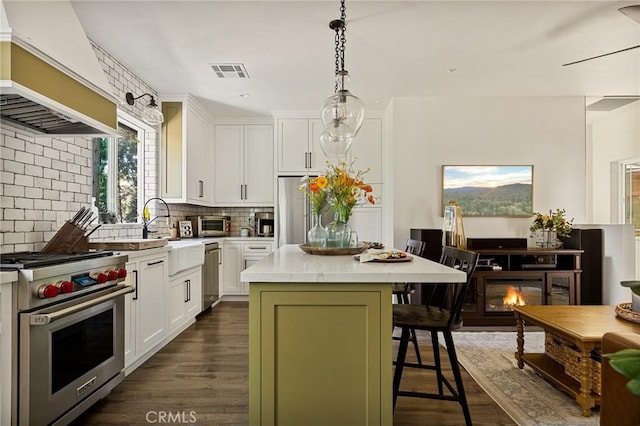 kitchen with white cabinetry, a center island, stainless steel appliances, premium range hood, and a kitchen breakfast bar