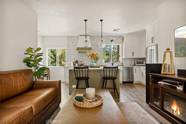 kitchen with hanging light fixtures, a kitchen island, stainless steel dishwasher, white cabinets, and a breakfast bar area