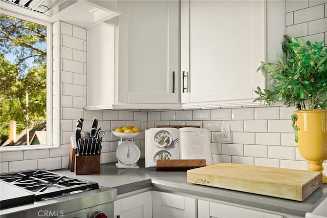 interior details featuring tasteful backsplash, white cabinetry, and range