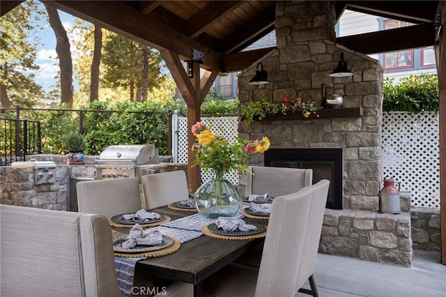 view of patio / terrace with grilling area, an outdoor stone fireplace, exterior kitchen, and a gazebo