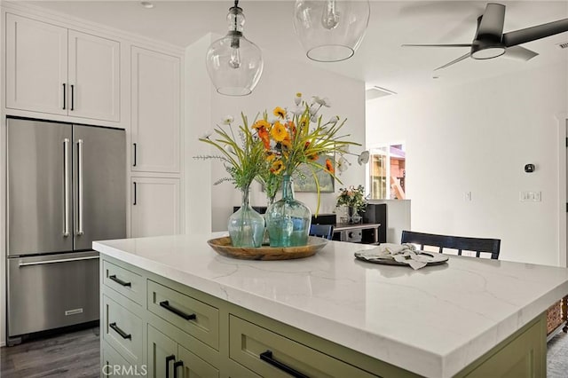 kitchen featuring light stone counters, green cabinets, a center island, high end refrigerator, and dark hardwood / wood-style floors