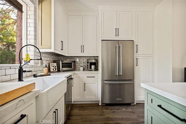 kitchen with appliances with stainless steel finishes, sink, dark hardwood / wood-style floors, white cabinets, and decorative backsplash