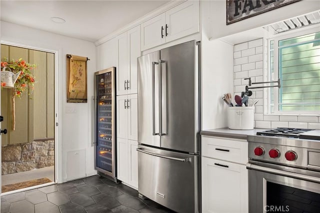 kitchen featuring appliances with stainless steel finishes, white cabinetry, beverage cooler, and backsplash