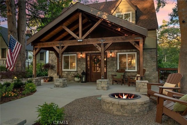 back house at dusk with a patio area and an outdoor fire pit