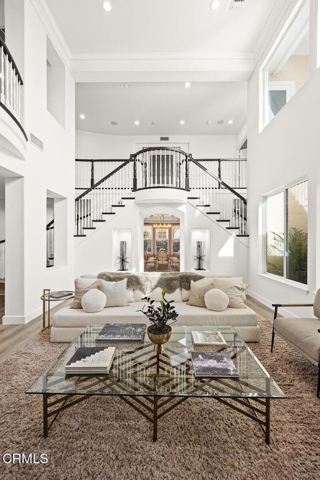 living room with a high ceiling, crown molding, and wood-type flooring