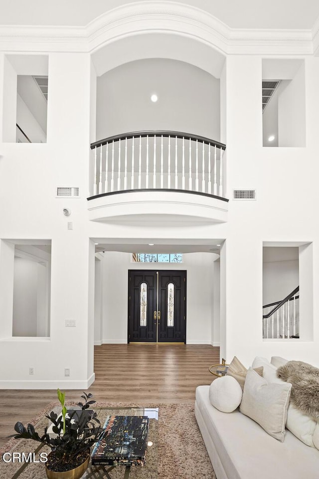 living room featuring hardwood / wood-style floors, crown molding, and a high ceiling