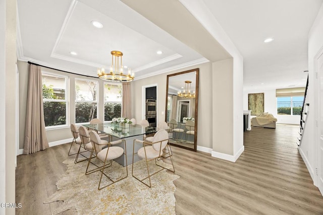 dining area featuring a raised ceiling, crown molding, an inviting chandelier, and light hardwood / wood-style flooring