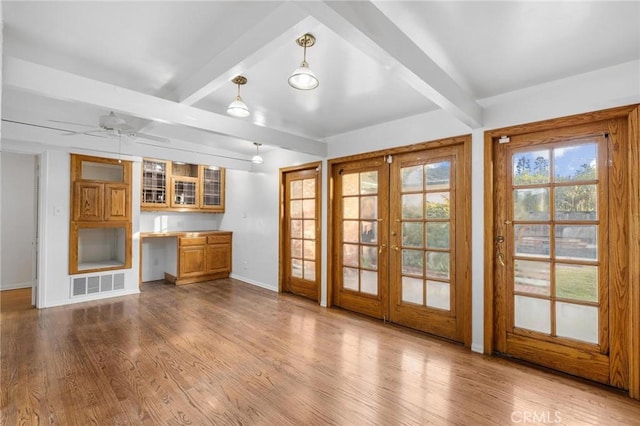 unfurnished living room featuring light hardwood / wood-style floors, french doors, and beam ceiling