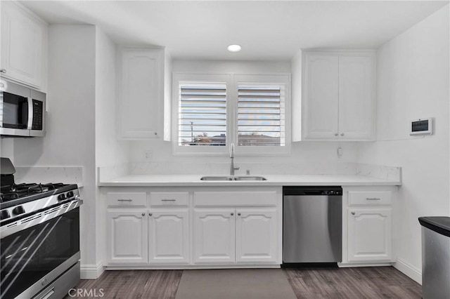 kitchen featuring light countertops, appliances with stainless steel finishes, a sink, and white cabinets