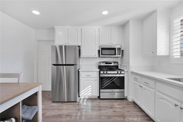 kitchen with light wood-style flooring, recessed lighting, stainless steel appliances, white cabinetry, and light countertops