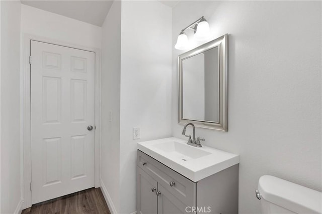 bathroom featuring baseboards, vanity, toilet, and wood finished floors