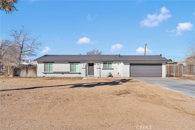 ranch-style home with driveway, an attached garage, fence, and stucco siding