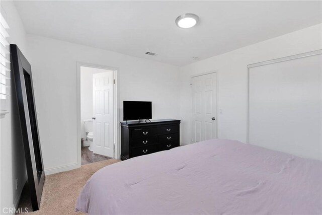 bedroom with light carpet, ensuite bath, baseboards, and visible vents