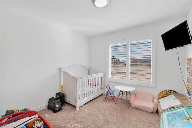 carpeted bedroom featuring a crib and baseboards