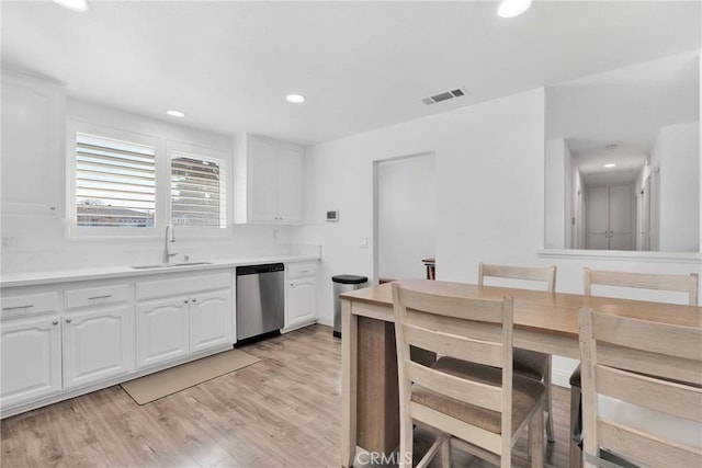 kitchen featuring light countertops, white cabinets, dishwasher, and a sink