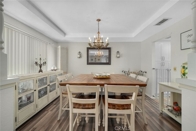 dining area featuring a raised ceiling, an inviting chandelier, and dark hardwood / wood-style floors