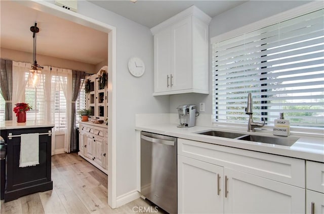 kitchen featuring sink, stainless steel dishwasher, white cabinetry, and a wealth of natural light