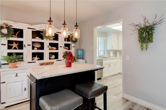 kitchen featuring a kitchen bar, sink, a kitchen island, and stainless steel dishwasher